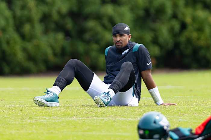 Philadelphia Eagles quarterback Jalen Hurts sits on the ground during practice.